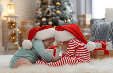 Canvas Print - Cute children in Santa hats on floor in room with Christmas tree