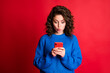 © deagreez - Photo of funny charming cute lady wavy hairdo hold telephone lips look screen excited amazed read fake news wear blue knitted sweater pullover isolated red color background