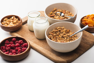 Wall Mural - delicious granola with nuts, fruits and yogurt on wooden board on white background