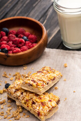 Canvas Print - delicious muesli bars on napkin with blurred glass of milk and berries on background