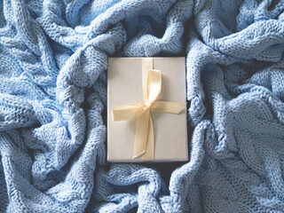 Wall Mural - Beautiful white package for presents on the cute pale blue wool knitted background.