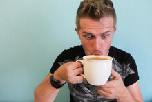 Young Handsome Man Addicted To Coffee. Coffeemania. Man Drinking Coffee Funny