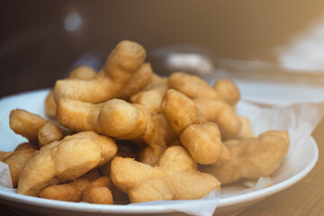 Wall Mural - Patongko or deep-fried dough sticks, traditional morning snack or breakfast of Thai and Chinese, close up Patongko or deep-fried dough sticks in white plate.