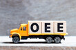 Truck hold letter block in word OEE (abbreviation of overall equipment effectiveness) on wood background
