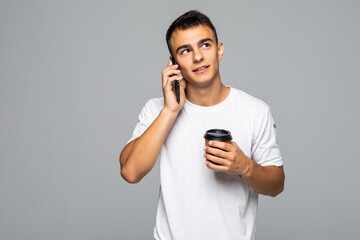 Wall Mural - Portrait of happy man talking on phone and drinking coffee isolated on gray background