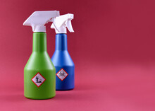 Plastic Spray Bottle With Toxic Liquid And Hazard Symbol Stock Images. Household Chemistry Photo. Container With Poisonous Liquid. Plastic Spray Bottle Isolated On A Red Background With Copy Space