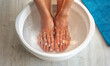 Woman put hands and feet in bath with hot water and baking soda at home. Homemade bath soak for dry feet skin