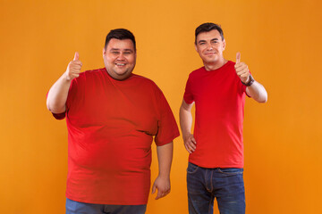 Fat and thin guys in red t-shirt. Two men with different complexion isolated on a yellow background. Ectomorph and endomorph