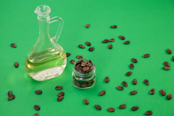 Wall Mural - Watermelon oil from seeds in a bottle, seeds are scattered around, a jar full of seeds on a green background