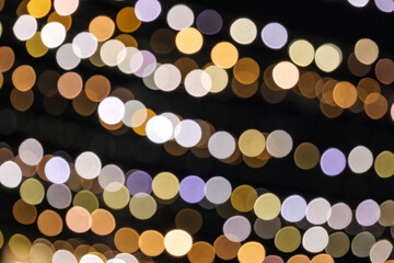 Wall Mural - Light gold purple and blue Christmas light shiny abstract round bokeh on black background. Colourful Glitter bokeh from blurry decoration bulbs.
