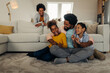 © bernardbodo - Afro family in the living room. Father tickling his children
