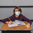© 3Days2Go Media - Young male student with virus mask sitting and studying in classroom