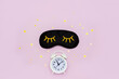 © ClareM - Sleep mask, alarm clock and starry confetti on pink background. Waking up concept. Flatlay, top view
