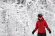 © Maridav - Winter sport happy skier Alpine skiing going dowhill against snow covered trees background during winter snowstorm. Woman in red jacket and goggles.