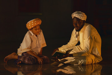 muslim boy sitting in mosque with islamic teacher learning koran book