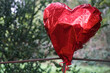 Party is over deflated red heart balloon object for birthday party or love valentines day on green trees background. st. Valentines day. 14th february. afterparty.