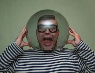 male wear glasses  for diving and holding aquarium above head isolated on green wall background.