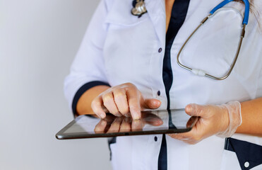 Female physician using digital tablet while standing near desk at clinic emergency hospital.