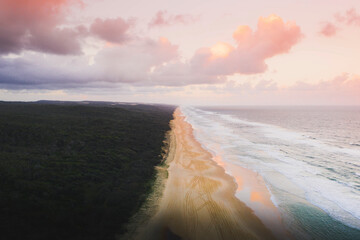 Drone view of coastline under a pastel pink sky