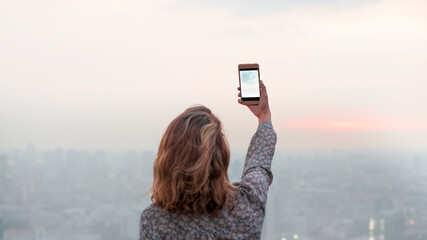 Wall Mural - Woman capturing a photo of the sunset