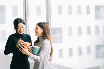 Wall Mural - Two Asian business women were chatting by the window during recess
