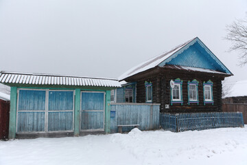 Vintage wooden rural house with ornamental carved windows, frames in Alyoshkino village, Mari El Republic, Russia. Russian folk style in wooden architecture. Snow