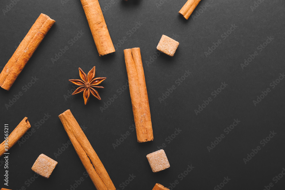 Cinnamon sticks, sugar and anise on dark background