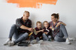 © Andrii Lysenko - family of four people sit on the floor near the wall.