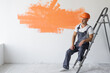 © Andrii Lysenko - a man in overalls is sitting on a ladder. Protective orange helmet on the head.