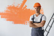 © Andrii Lysenko - young stylish Caucasian man dressed in overalls and orange safety helmet.