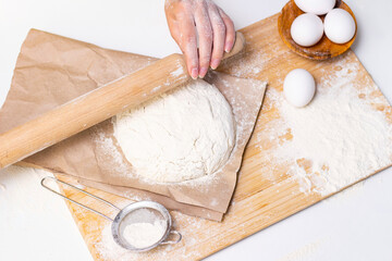 Home cooking concept. Female hands prepare homemade dough on a floured wooden board.