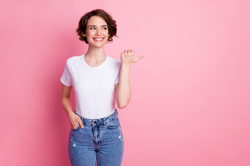 Portrait of attractive cheerful brown-haired girl showing thumb advert copy empty blank space isolated over pink pastel color background