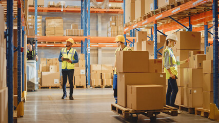 Wall Mural - Handsome Male Worker Wearing Hard Hat Holding Digital Tablet Computer Walking Through Retail Warehouse full of Shelves with Goods. Professional People Working in Logistics and Distribution Cente