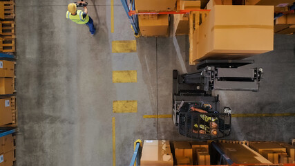 Wall Mural - Top-Down Shot: Electric Forklift Truck Operator Lifts Pallet with Cardboard Box of in a Big Retail Warehouse a Shelf. Logistics Product and Goods Delivery and Distribution Center