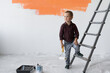 © Andrii Lysenko - A young boy with a serious look stands in a room near the stairs. Holds a paint brush in his hands.