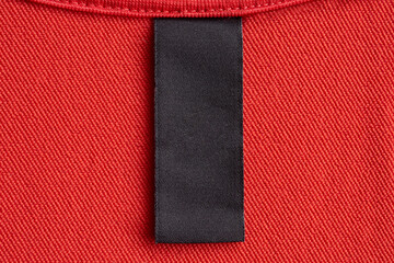 Wall Mural - Blank black laundry care clothes label on red fabric texture background