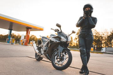 Brutal biker near motorcycle on the background of a gas station