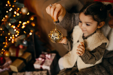 Mother and daughter decorating christmas tree at home.