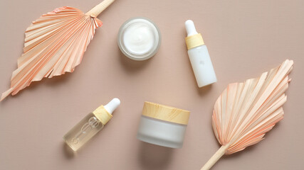 Wall Mural - natural cosmetic cream jars, serum, essential oil dropper bottle, dry flowers leaves on beige backgr