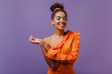 Wall Mural - Cheerful laughing african woman smiling on purple background. Charming black girl enjoying studio photoshoot.