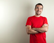 Studio photo of smiling man in his 30s with crossed arms wearing a red t shirt. Isolated on bright background.