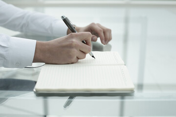 Office worker's hand writes in notebook