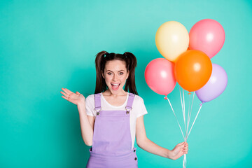 Poster - Photo of lovely young girl hold balloons waving palm open mouth wear purple overall isolated teal color background