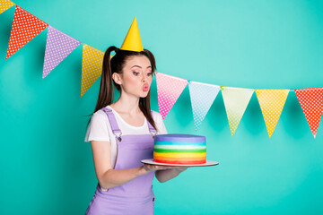 Sticker - Side profile photo portrait of happy birthday girl wearing cone keeping cake with pouted lips isolated on vivid teal color background