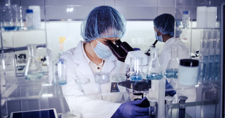 Wall Mural - female science team working on biohazardous samples. using microscope and computer with data
