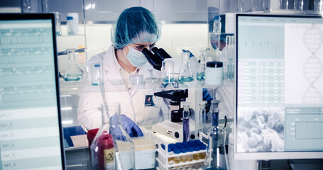 Wall Mural - female science team working on biohazardous samples. using microscope and computer with data