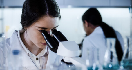 Wall Mural - multi ethnic science team working with microscope and computer. female doctors in futuristic laborat