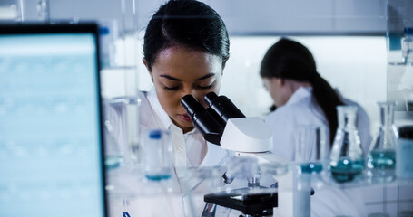 Wall Mural - multi ethnic science team working with microscope and computer. female doctors in futuristic laborat