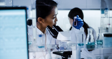 Wall Mural - female doctors testing samples in futuristic laboratory. using microscopes and computer with data