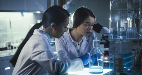 Wall Mural - multi ethnic female scientists working late in labolatory. using microscope